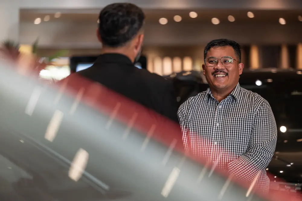 A sales representative speaking with a client at Tristram Omoda car dealership.